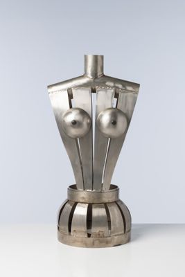 une sculpture en argent représentant un mannequin posé sur une table blanche