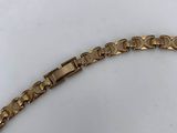 a close up of a gold bracelet on a white surface