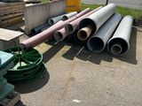 a pile of pipes sitting on the ground next to a pile of pallets