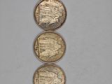 three gold coins sitting on top of each other on a white surface