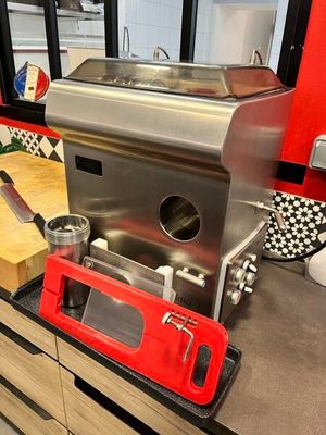 cafetière en acier inoxydable posée sur le plan de travail de la cuisine, avec des placards rouges