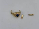 a gold ring with a blue stone sits on top of a white surface