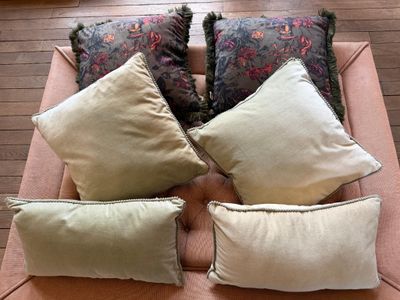 plusieurs coussins posés sur un canapé rose dans une pièce au sol en parquet