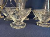 three clear glass cups and a pitcher on a blue table