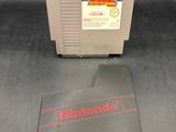 Un vieux jeu Nintendo est posé sur une table, à côté d'un livre.