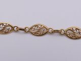 a close up of a gold bracelet on a white surface