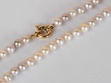 a close up of a white pearl necklace with a gold clasp