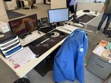 a man standing in front of a computer desk with a blue shirt on it