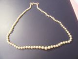 collier composé de perles blanches et d'un fermoir doré sur un fond noir