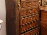 a wooden chest of drawers in a room with a chair