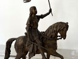 une statue représentant un homme à cheval tenant un drapeau