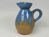 a blue and yellow vase sitting on a white surface