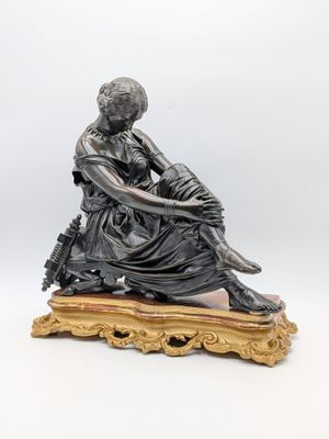 une figurine antique en bronze représentant une femme assise sur un socle en bois