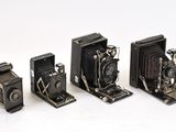 quatre appareils photo anciens sont alignés sur une surface blanche
