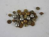 a pile of silver and gold buttons on a white surface