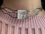 a close up of a woman wearing a necklace with a picture of a lion on it
