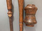 two wooden pepper grinders and a wooden pepper mill on a wall