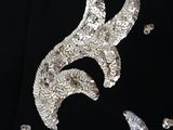 silver sequins are scattered on a black shirt with a bird on it