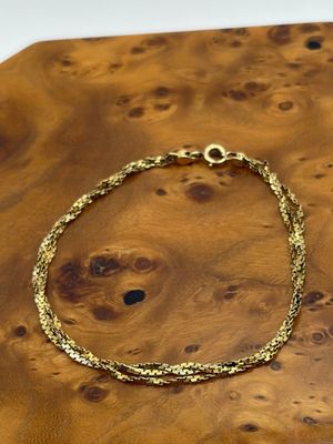 un gros plan d'un bracelet en or posé sur une table en bois