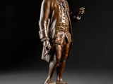a bronze statue of a man holding a glass of wine