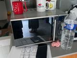 un micro-ondes posé sur un plan de travail, à côté d'un verre d'eau et d'un téléphone portable