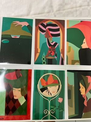 several cards of women with hats and umbrellas on a table