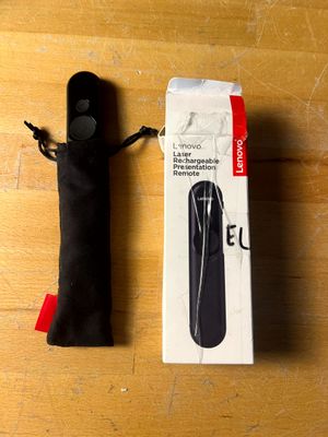 une télécommande noire posée sur une table à côté d'un sac noir