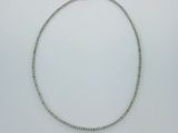 gros plan d'un collier en argent sur une surface blanche
