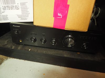 une boîte posée sur une chaîne hi-fi qui se trouve sur une étagère