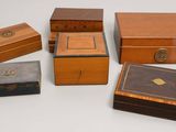 six petites boîtes en bois sont alignées sur une surface blanche
