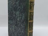 un vieux livre à la couverture verte posé sur une surface blanche