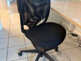 a black office chair sitting in front of a computer desk