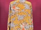 a yellow floral shirt on a mannequin stand against a red background