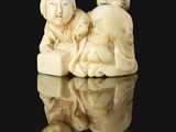 two ivory figurines of a woman and a child on a black surface