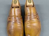 pair of brown leather shoes on grey surface with one shoe in the middle of the shoe