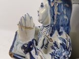 a blue and white figurine of a man reading a book
