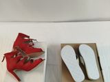 two pairs of red shoes in a box on a bed
