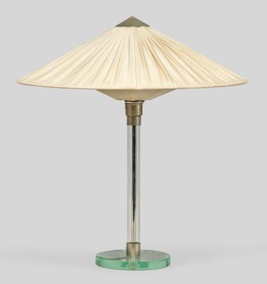 une lampe de table en verre vert surmontée d'un abat-jour blanc