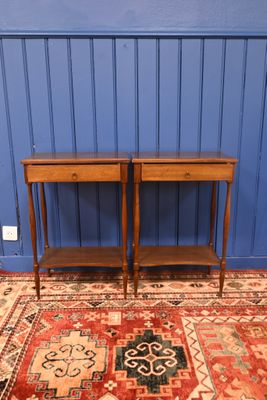 une paire de tables d'appoint anciennes posées sur un tapis devant un mur bleu