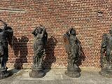 Trois statues de femmes se dressent devant un mur de briques
