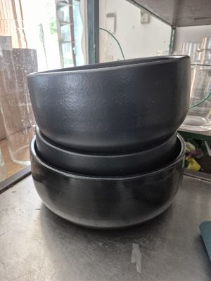 trois casseroles noires empilées les unes sur les autres sur une table