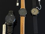 three watches are sitting on a black surface with a price tag
