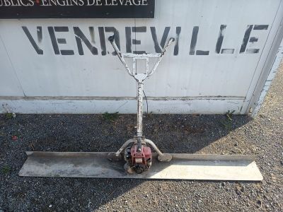 une petite machine posée par terre à côté d'un panneau
