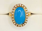 a close up of a gold ring with a blue stone and diamonds