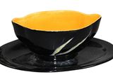 a black and yellow bowl and saucer on a black plate