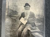 an old photo of a man with a long beard sitting on a bench