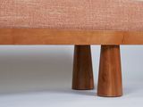 an upholstered bench with two wooden legs and a pink upholstered seat