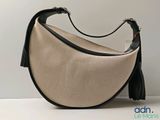 a beige purse with a black handle on a white table
