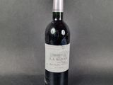 a bottle of wine sitting on top of a table next to a gray background