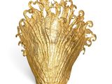 a gold vase that is sitting on a white surface